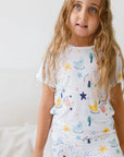 A girl wearing our Amara Short Sleeve Pyjama, glowing in pastel moon and star prints inspired by the lullaby “Amara ya Amara.”