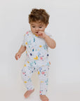 A baby wearing our Amara Short Sleeve Pyjama, exploring freely in soft bamboo fabric and whimsical moon-and-star prints.