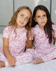 Two girls wearing our Amira Short Sleeve Pyjama, twinning in soft bamboo fabric and royal princess prints for dreamy nights.