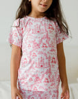 A girl wearing our Amira Short Sleeve Pyjama, glowing in soft bamboo comfort and the sweetest princess-inspired print.