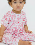 A little girl wearing our Amira Short Sleeve Pyjama, cozy in soft bamboo fabric and blooming with charming princess prints.