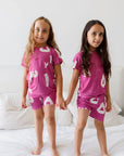 Two kids wearing our Arqam Short Sleeve Pyjama, featuring playful Arabic numbers on vibrant magenta bamboo fabric — comfy, breathable, and full of character.