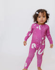 A curious little girl standing confidently while wearing our Arqam Smart Baby Pyjama, featuring bold Arabic numbers in a playful magenta print.