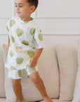 A playful boy standing on the couch while wearing our Ashta Loungewear set, featuring the fun annona fruit design.