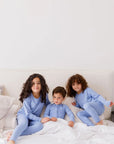 Three siblings sitting together on a cozy bed, all dressed in our Bahry Long Sleeve Kids Pyjamas, enjoying comfort in matching bamboo softness.