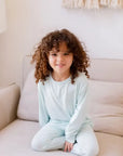 A young girl wearing the **Reef Pyjama** from the **Ramady & Reef Bundle**, a soft seafoam-blue long-sleeve set made from breathable bamboo fabric for cozy, all-day comfort.