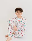 A cheerful boy sitting comfortably in our Christmas Long Sleeve Kids Pyjama, adorned with festive Levant-inspired designs that celebrate the holiday spirit.