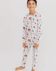 A smiling boy standing barefoot in our Christmas Long Sleeve Kids Pyjama, showcasing the festive Levant-inspired holiday print.
