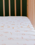 A close-up of our Nohm Harakat Crib Sheet, featuring playful Arabic-inspired patterns for a soft and cultural nursery touch.