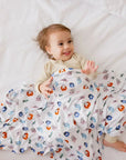 A smiling baby snuggled in our Nohm Tanween Bedding Set, wrapped in the playful comfort of its soft Arabic-inspired design.