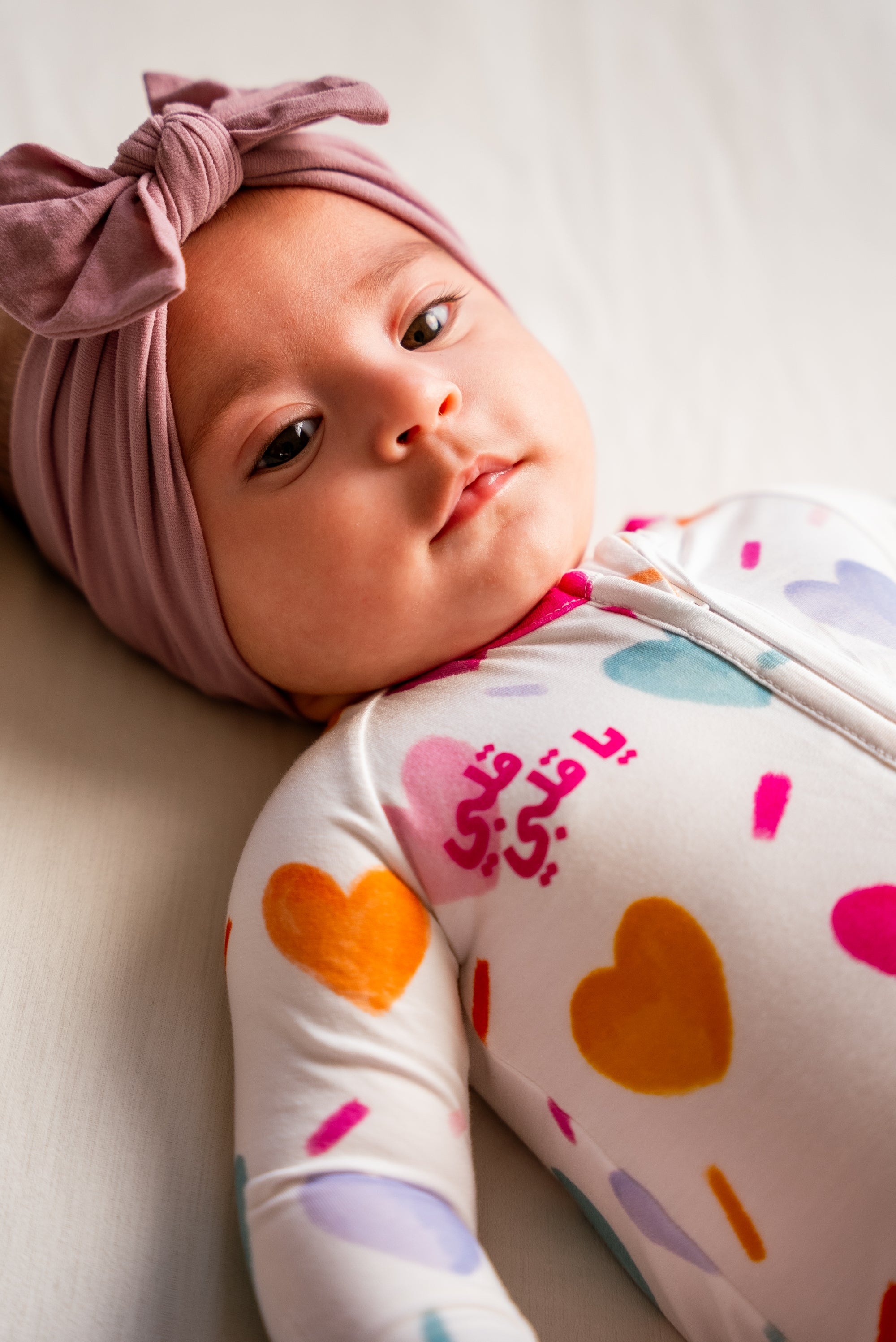 A baby wearing our Albi Smart Baby Pyjama, resting peacefully in the soft heart-print design with the sweet “يا قلبي” detail.