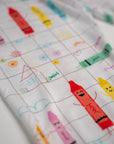 Close-up of our Crayons Pyjama fabric, featuring colorful Arabic crayon characters and playful hand-drawn doodles on a soft grid pattern.