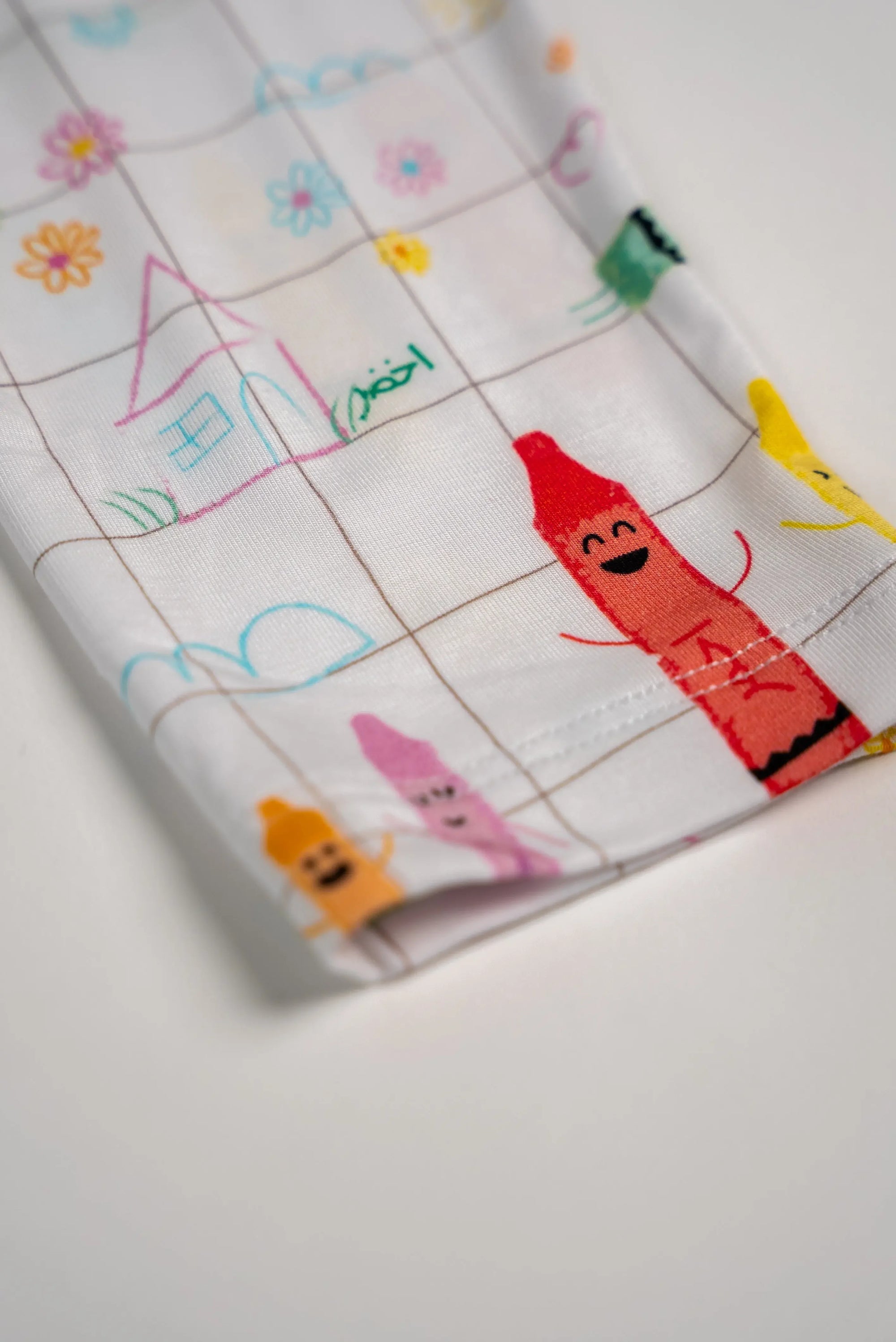 Detailed close-up of our Crayons Pyjama sleeve, showing the cheerful Arabic crayon prints and playful doodle patterns in soft pastel colours.