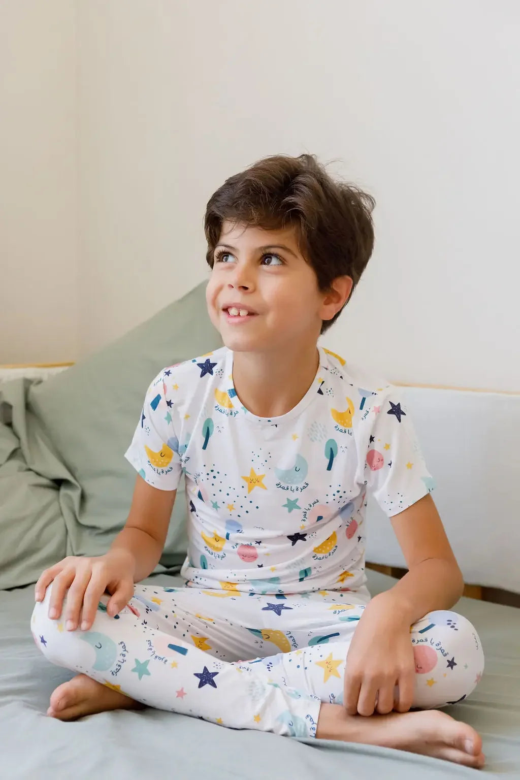 A child wearing our Amara Short Sleeve Pyjama, cozy in soft bamboo fabric with dreamy moon and star prints inspired by “Amara ya Amara.”