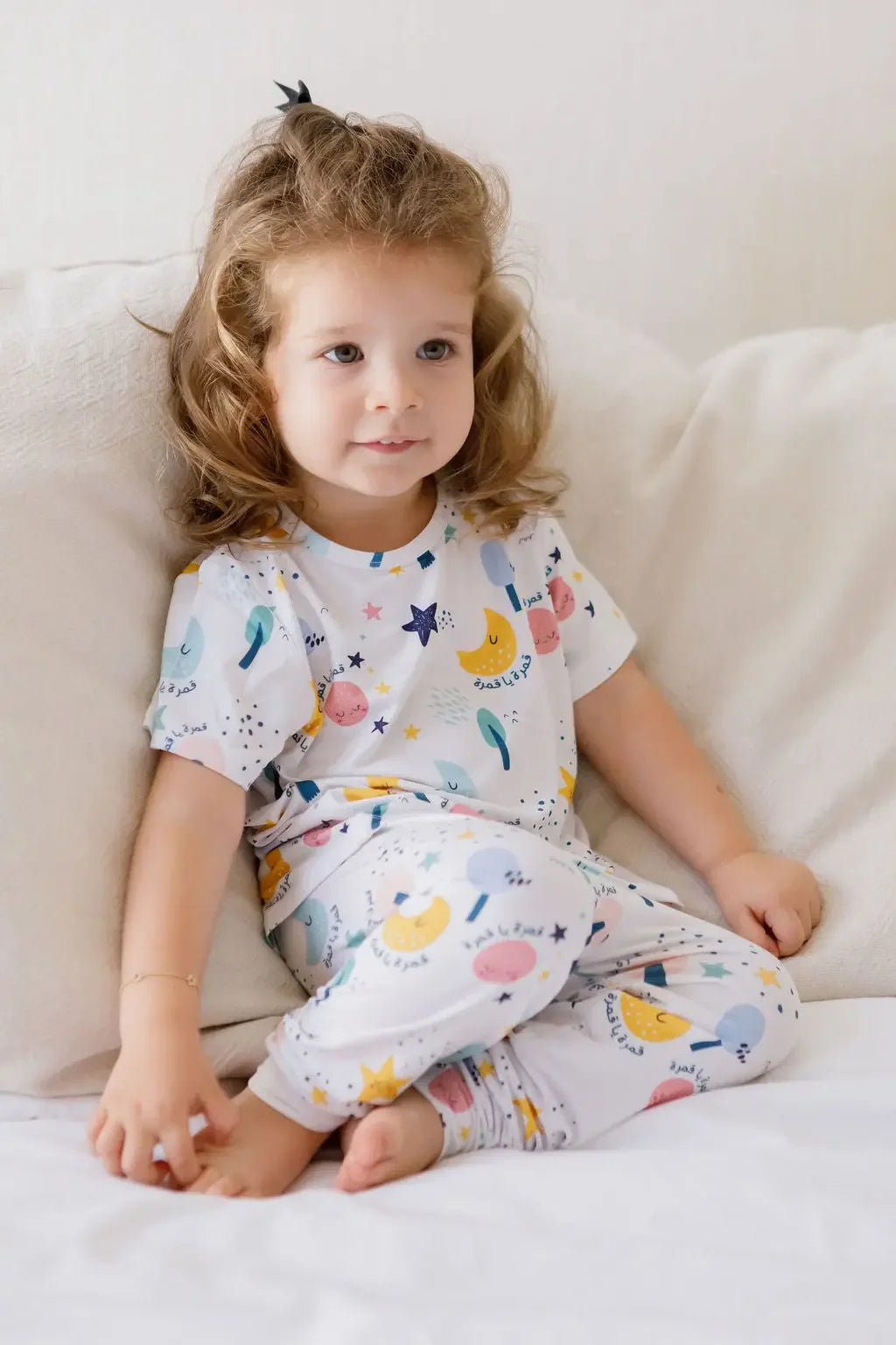 A little girl wearing our Amara Short Sleeve Pyjama, wrapped in soft bamboo comfort and dreamy moon-and-star prints.