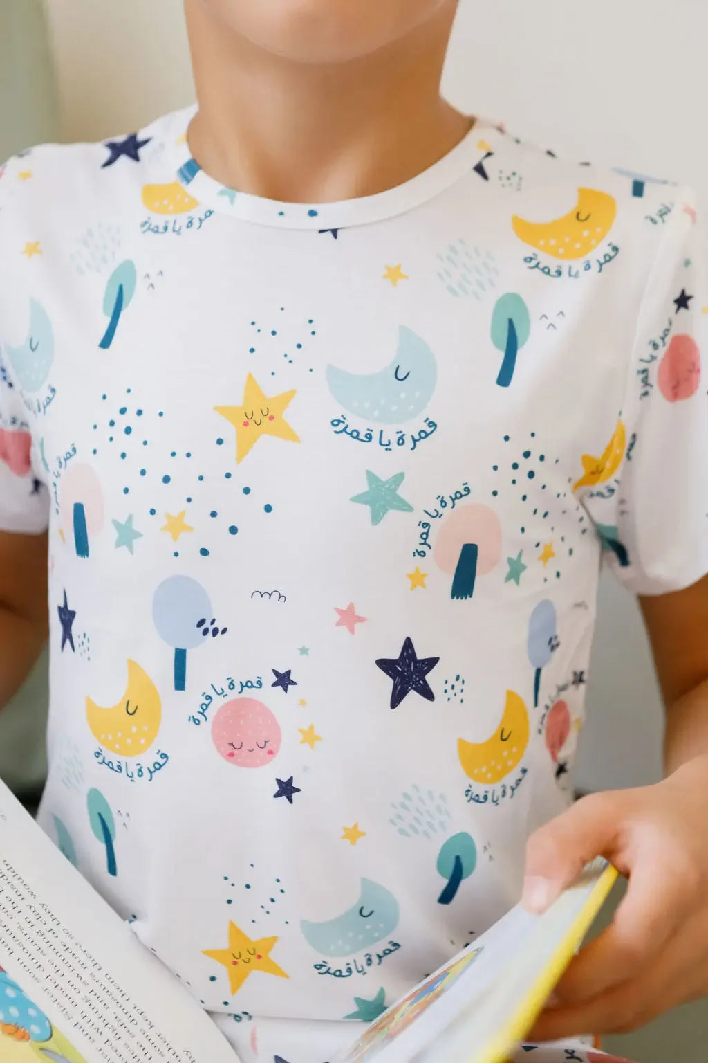 Close-up of our Amara Short Sleeve Pyjama featuring soft pastel moons, stars, and Arabic script from the lullaby “Amara ya Amara.”
