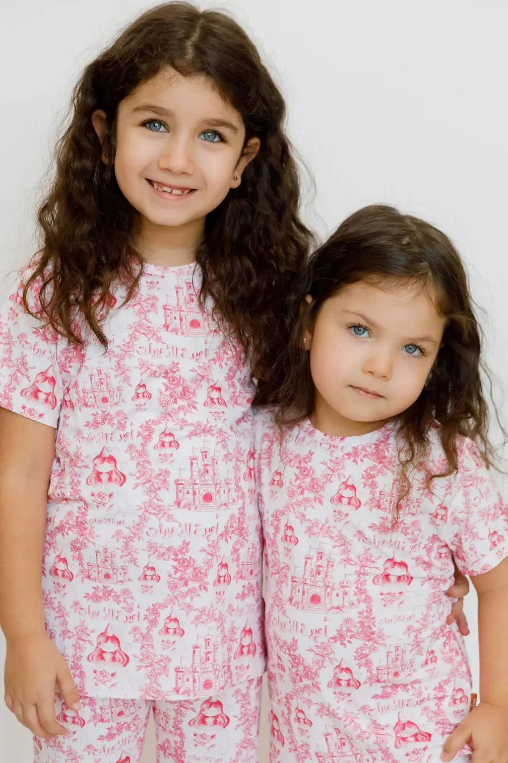 Two girls wearing our Amira Short Sleeve Pyjama, twinning in soft bamboo comfort and dreamy princess-inspired prints.
