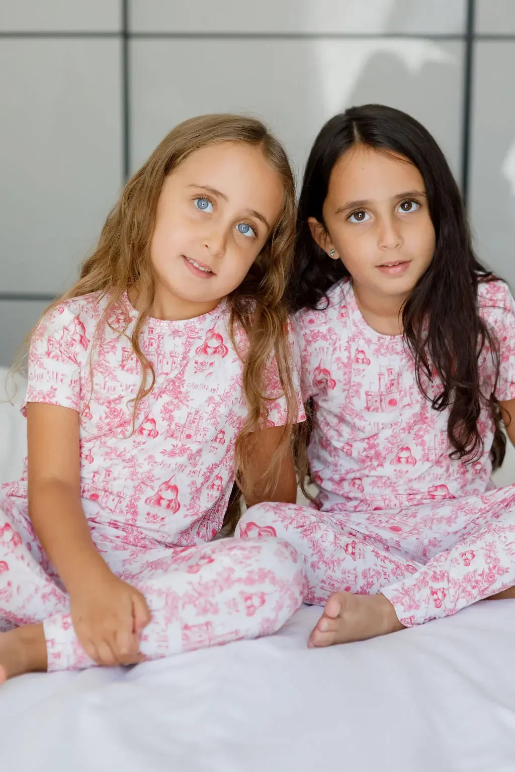 Two girls wearing our Amira Short Sleeve Pyjama, twinning in soft bamboo fabric and royal princess prints for dreamy nights.
