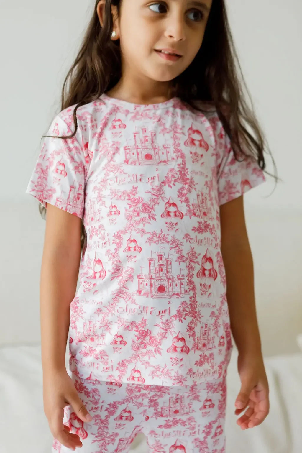 A girl wearing our Amira Short Sleeve Pyjama, glowing in soft bamboo comfort and the sweetest princess-inspired print.