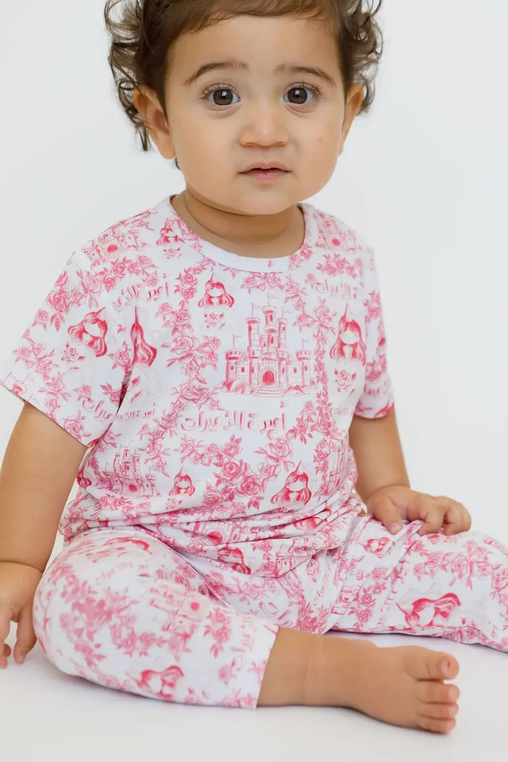 A little girl wearing our Amira Short Sleeve Pyjama, cozy in soft bamboo fabric and blooming with charming princess prints.