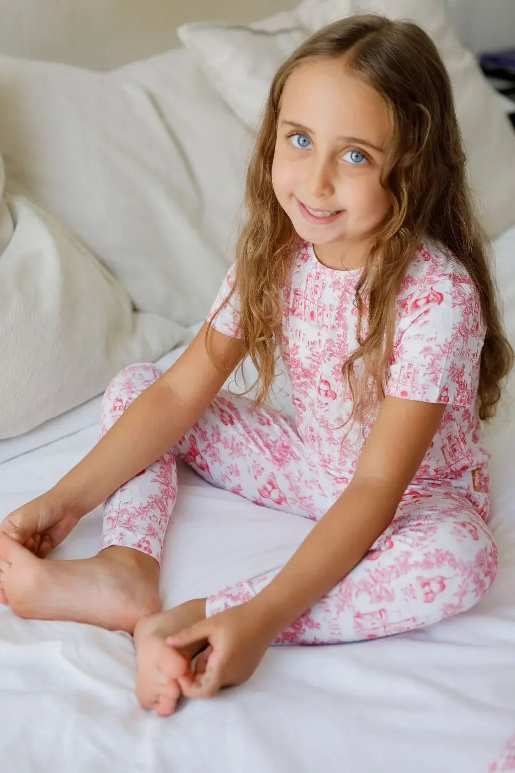 A girl wearing our Amira Short Sleeve Pyjama, smiling sweetly in the soft bamboo fabric and charming princess print.