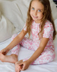 A girl wearing our Amira Short Sleeve Pyjama, smiling sweetly in the soft bamboo fabric and charming princess print.
