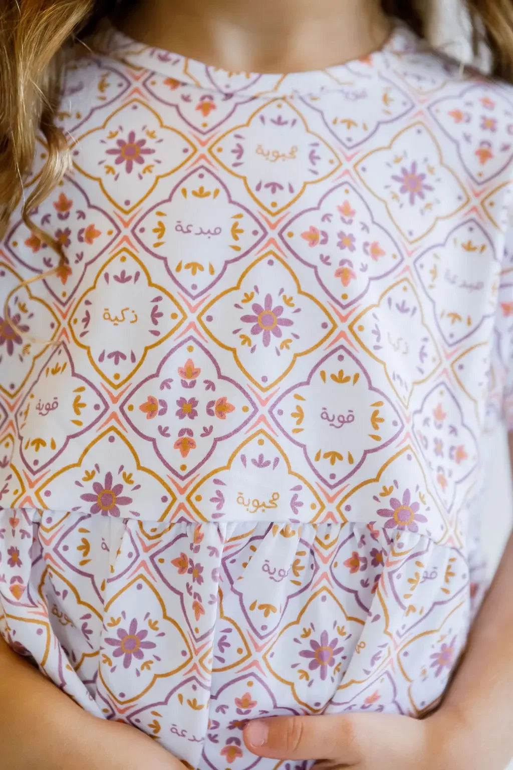 A close-up of our Arabesque Dress, featuring intricate tile-inspired patterns and Arabic words celebrating strength and grace.