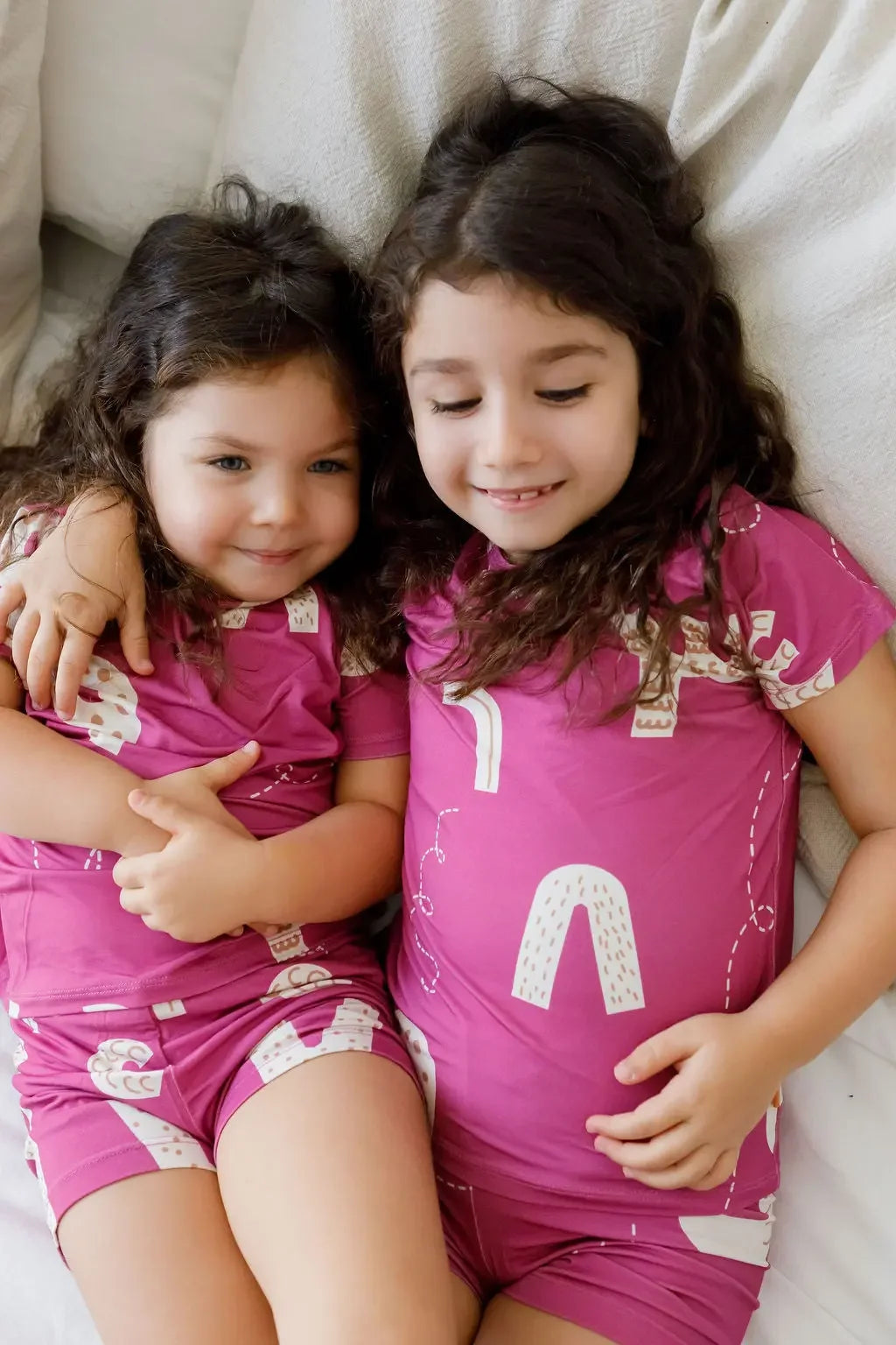 Sisters sharing cuddles in our Arqam Short Sleeve Pyjama, featuring playful Arabic numbers on soft, breathable bamboo fabric for cozy, matching moments.