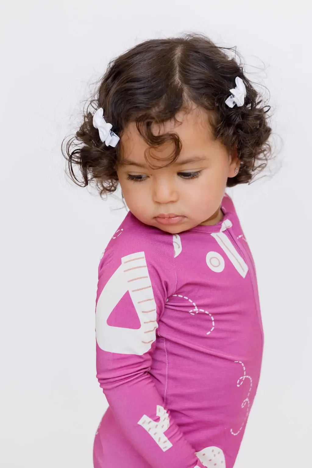 A thoughtful girl looking down while wearing our Arqam Smart Baby Pyjama, decorated with playful Arabic numbers for a cozy, educational twist.