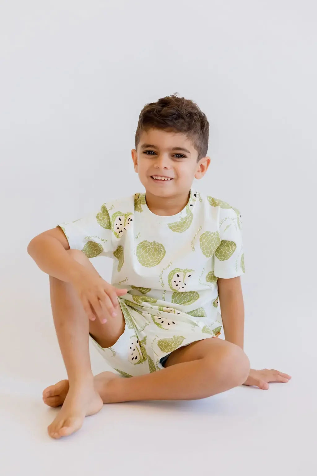 A relaxed boy sitting comfortably while wearing our Ashta Loungewear set, blending cozy comfort with playful annona-inspired style.
