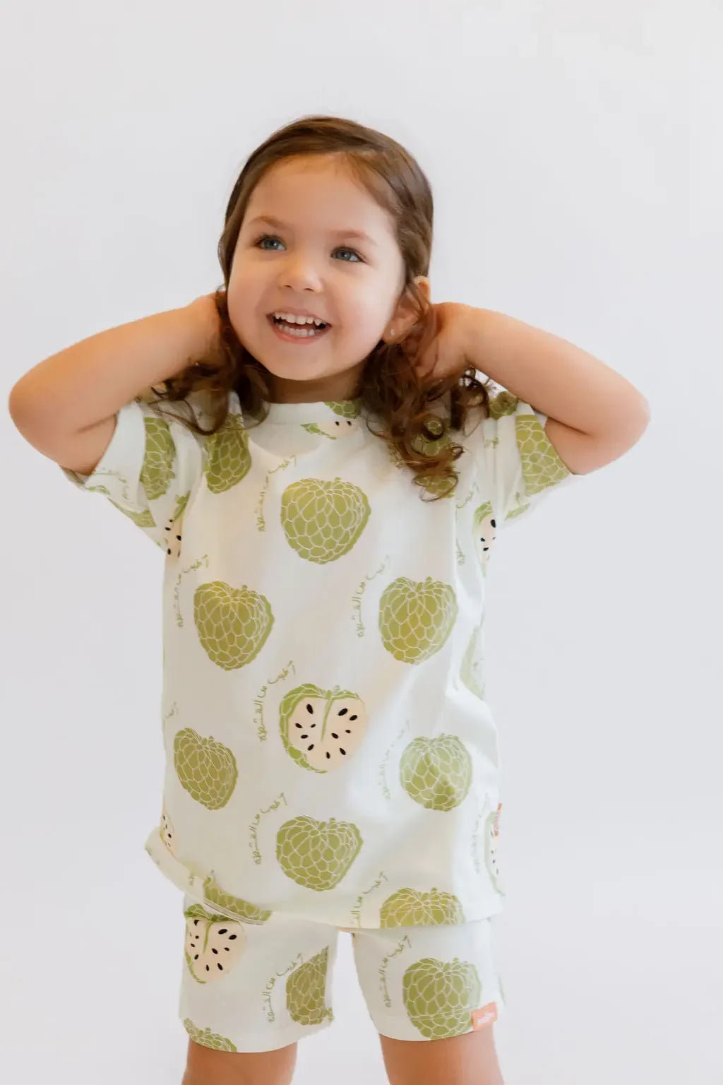 A joyful girl smiling brightly while wearing our Ashta Loungewear set, featuring the fun and fruity annona-inspired print.
