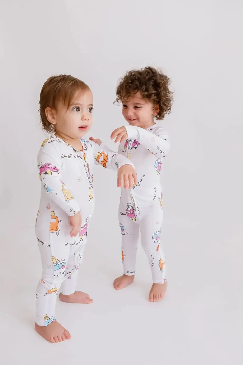 Two little ones wearing our Bosta Pyjamas, matching in playful Lebanese bus-inspired prints that celebrate culture and comfort.