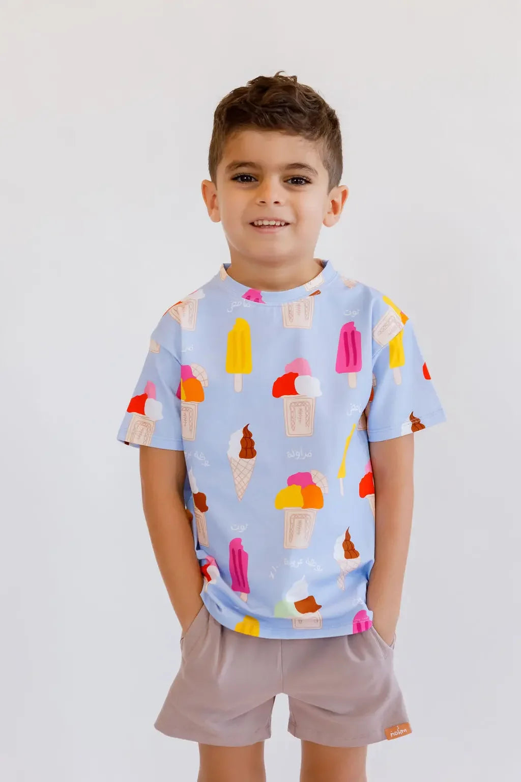 A smiling boy standing with his hands in his pockets, wearing our Boza Loungewear set covered in playful ice cream prints.