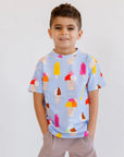 A smiling boy standing with his hands in his pockets, wearing our Boza Loungewear set covered in playful ice cream prints.