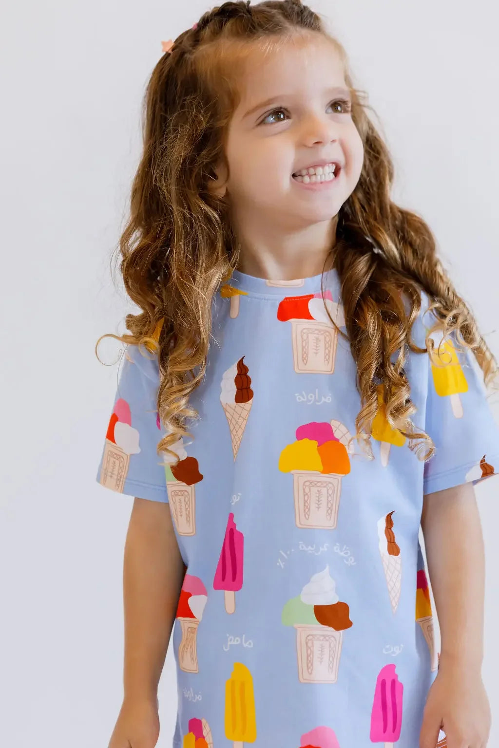 A happy girl looking up with a bright smile while wearing our Boza Loungewear set, bursting with colorful ice cream prints.