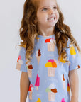 A happy girl looking up with a bright smile while wearing our Boza Loungewear set, bursting with colorful ice cream prints.