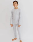 A young boy wearing the **Ramady Pyjama** from the **Ramady & Reef Bundle**, a soft light-gray long-sleeve set designed for all-night comfort and a relaxed fit.