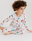 A cheerful boy wearing our Christmas Long Sleeve Kids Pyjama, surrounded by festive lights and Levant-inspired patterns that celebrate the holiday spirit.