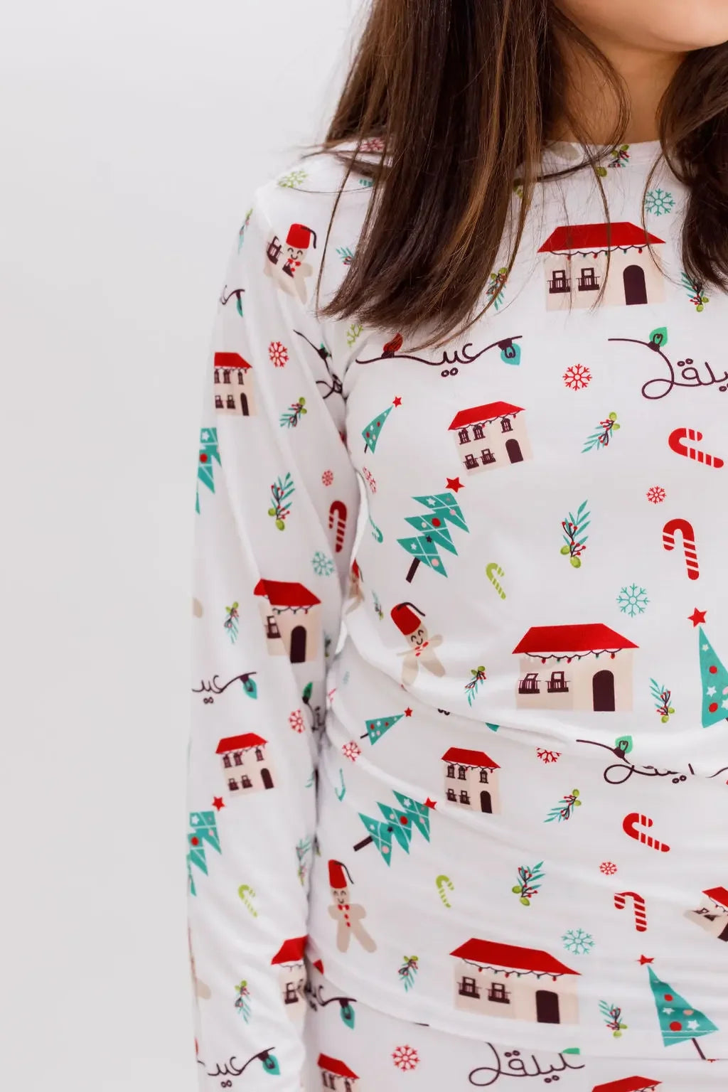 A close-up of our Christmas Long Sleeve Kids Pyjama, highlighting the Levant-inspired festive print with stone houses, pine trees, and candy canes.