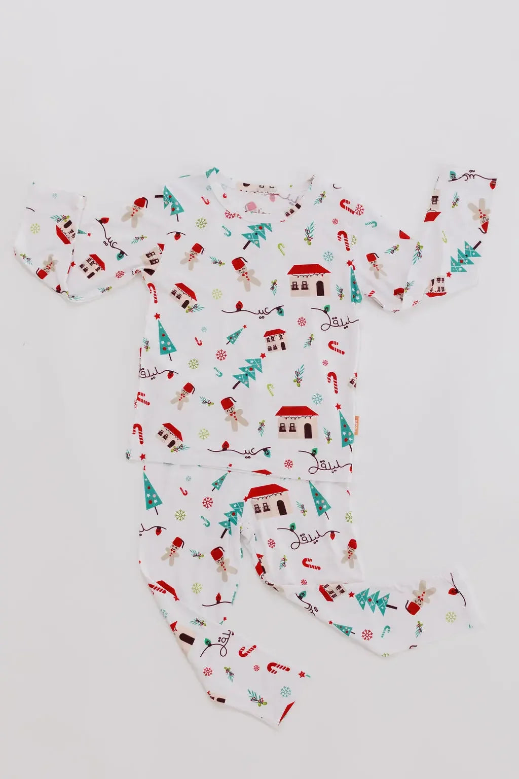 Our Christmas Long Sleeve Kids Pyjama laid flat, showcasing the festive Levant-inspired print with charming houses, trees, and holiday icons.