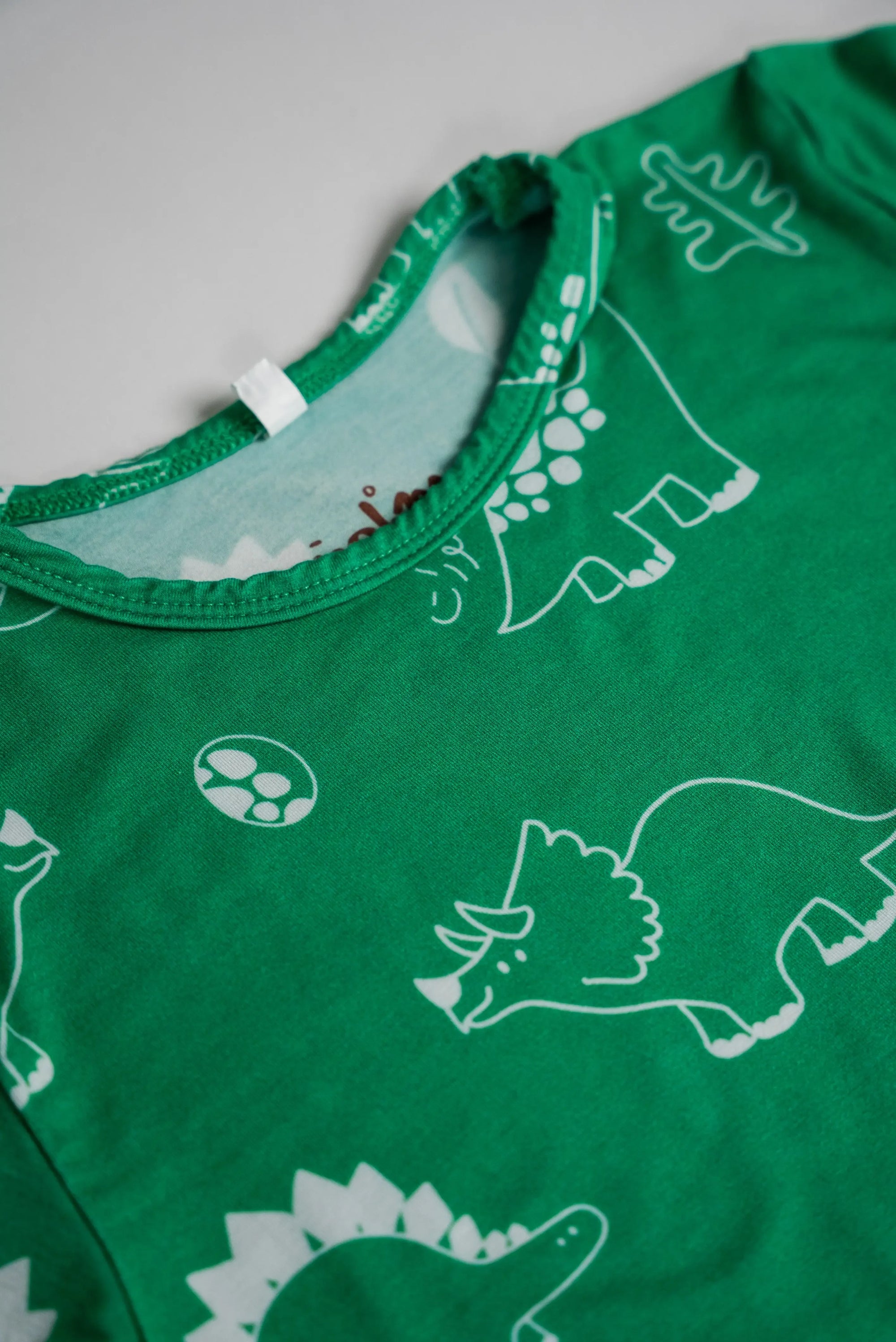 Close-up of our Dinosaur Pyjama top, highlighting the fun white dinosaur prints and soft green bamboo fabric.