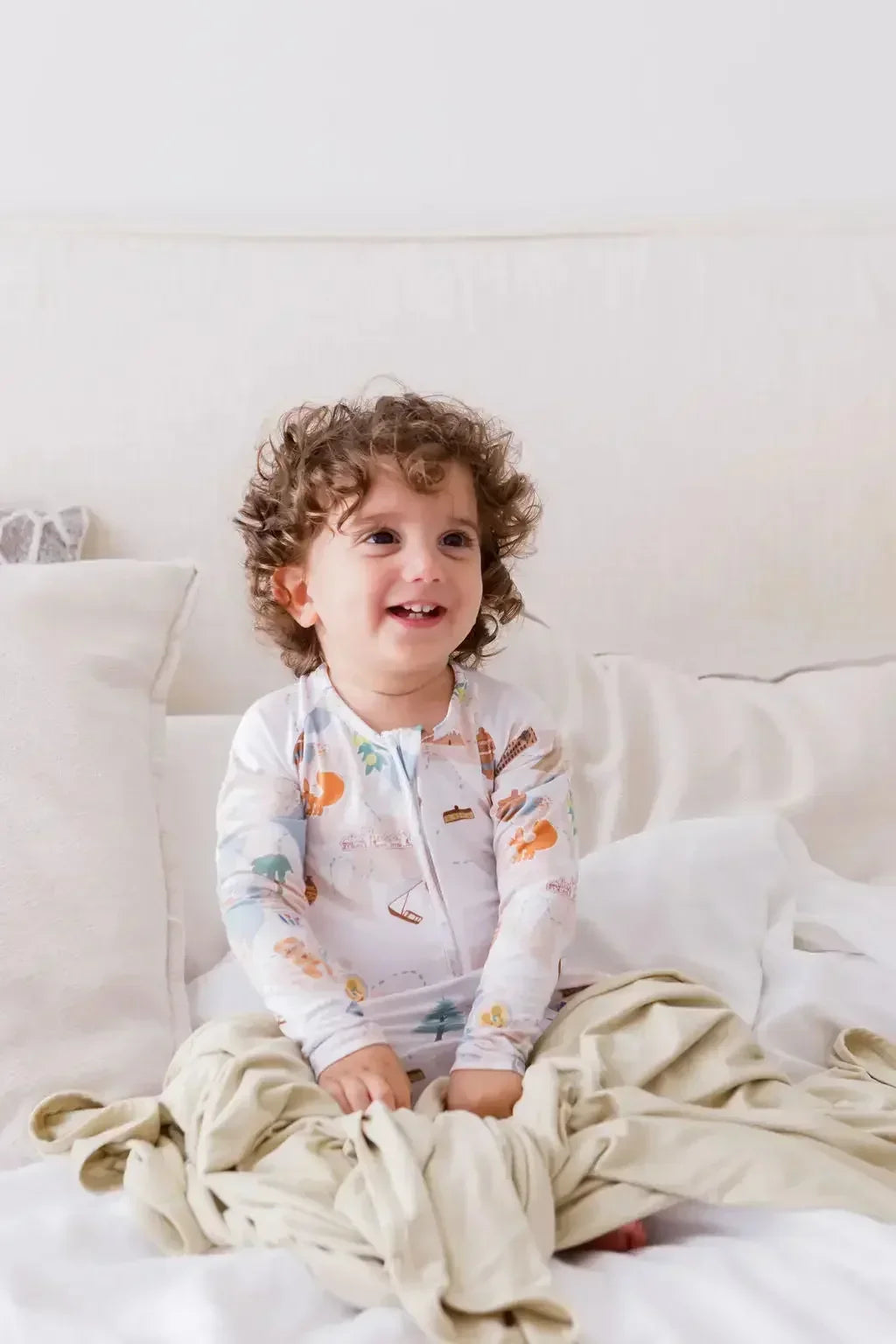 A baby sitting happily on our Nohm Ramly Bedding Set, enjoying the softness and calm of its minimalist bamboo design.