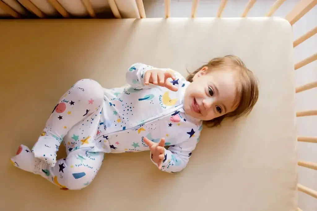 A baby lying happily on our Nohm Ramly Crib Sheet, enjoying the soft and breathable comfort of its bamboo fabric.