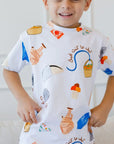 A smiling boy showing off our Lebanon T-Shirt, featuring playful prints of Lebanese icons like Man2ouche and Bonjus.