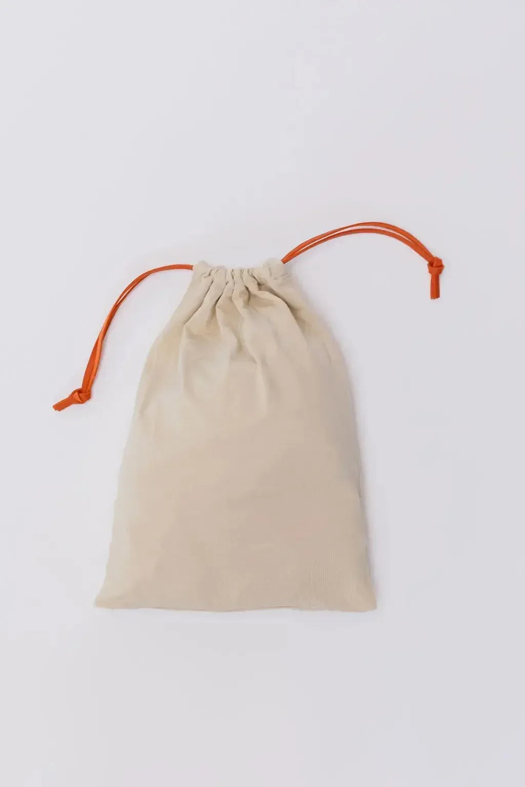 A soft beige Nohm pouch with orange drawstrings, designed to neatly hold the pieces of our Nohm Luxury Bedding Gift Set.
