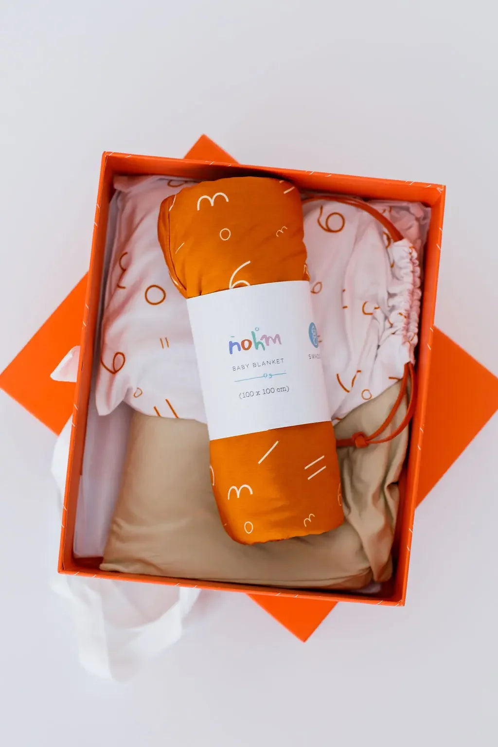 A cozy newborn bedding gift set beautifully arranged in an orange box, featuring our **Nohm Luxury Bedding Gift Set** made from ultra-soft, breathable bamboo fabric.