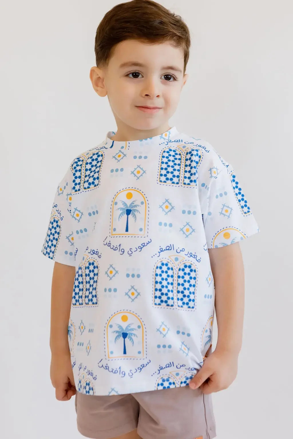 A young boy smiling proudly while wearing our Saudi T-Shirt, featuring the palm and “سعودي وأفتخر” design that celebrates national pride.
