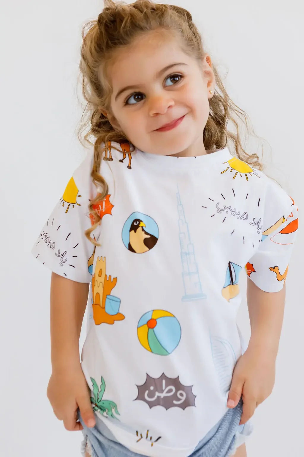 A little girl smiling confidently while wearing our playful UAE T-Shirt, celebrating the nation’s vibrant spirit.
