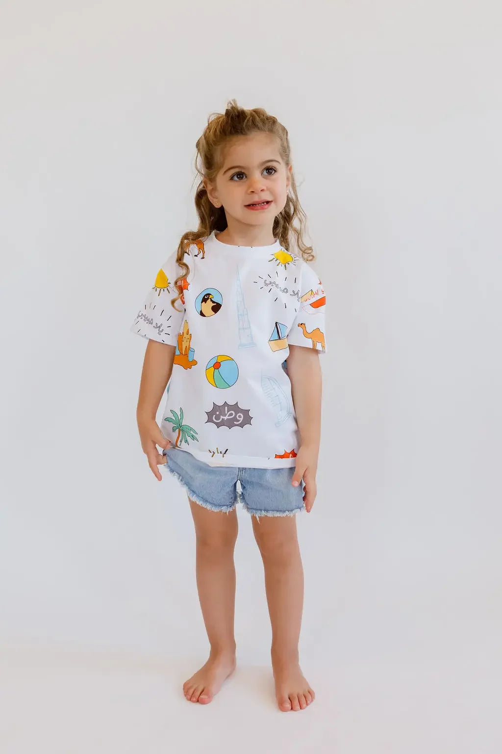 A happy girl standing tall in our UAE T-Shirt, proudly wearing a design that celebrates the nation’s colorful spirit.