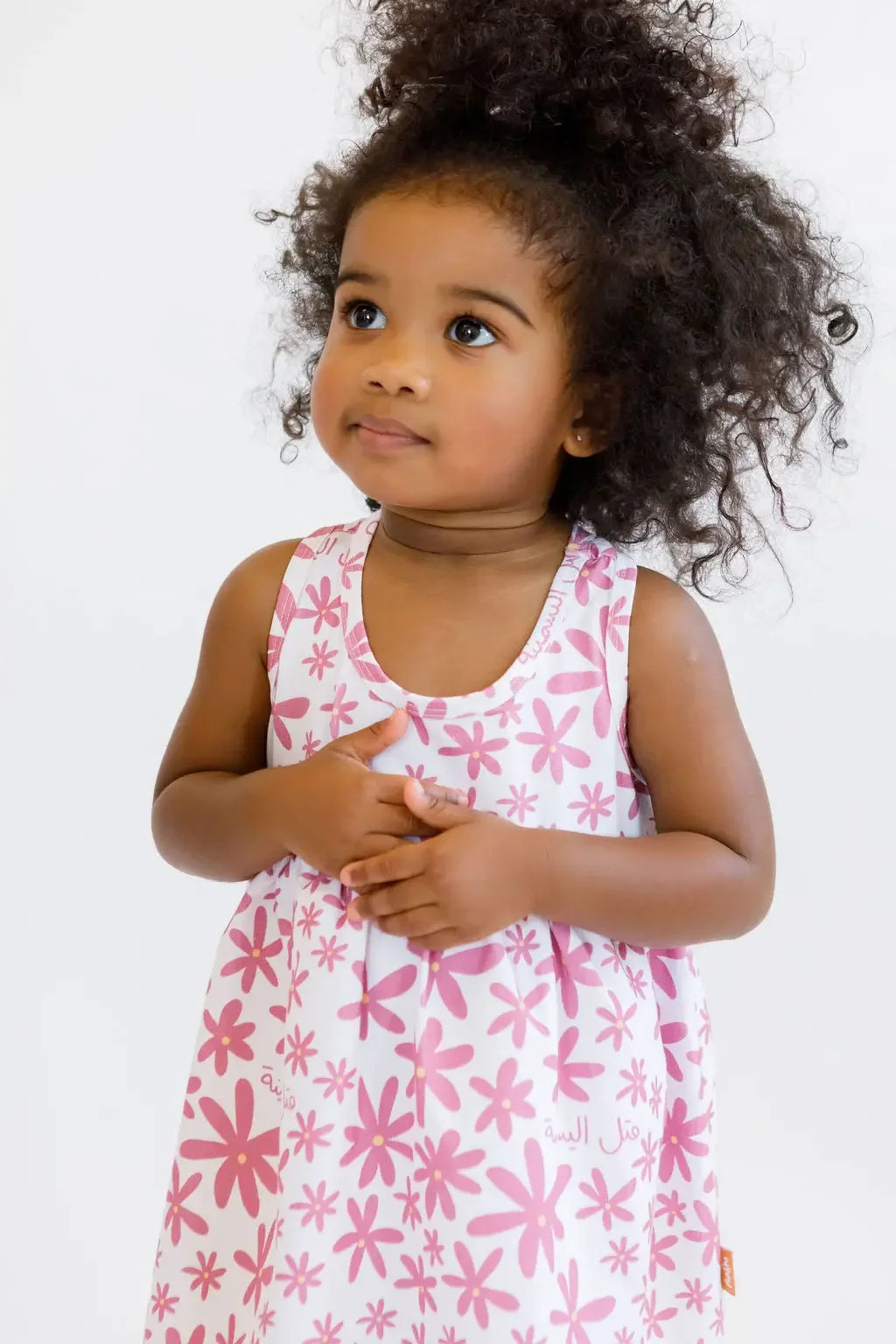 A sweet girl standing gracefully while wearing our Yasmine Dress, adorned with pink jasmine flowers for a soft, elegant look.